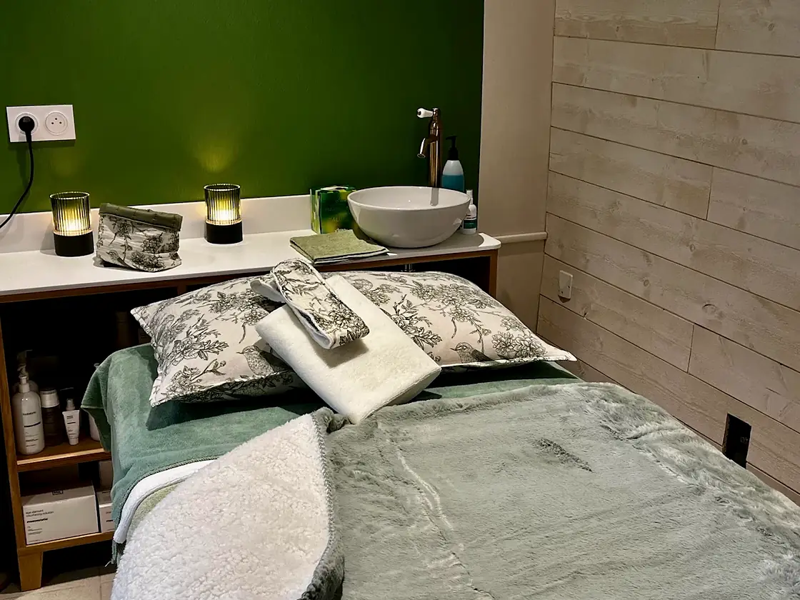 La cabine de soin, lit préparé devant le mur vert